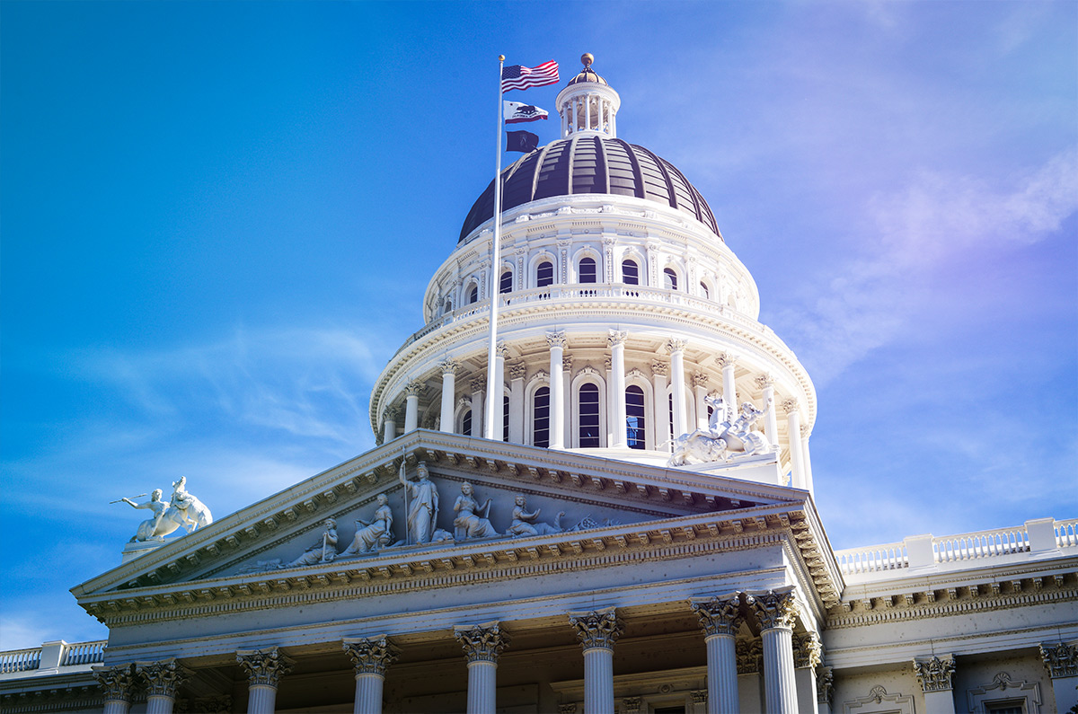 White building with columns around it, an American flag and below it the California state flag