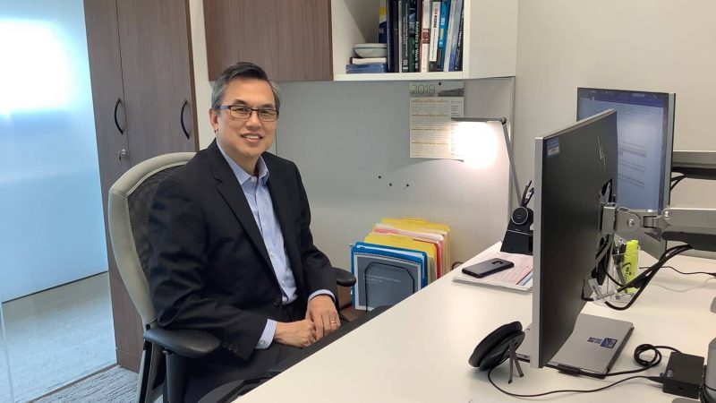 A professional seated at a desk in an office, surrounded by resources and materials for community engagement initiatives.