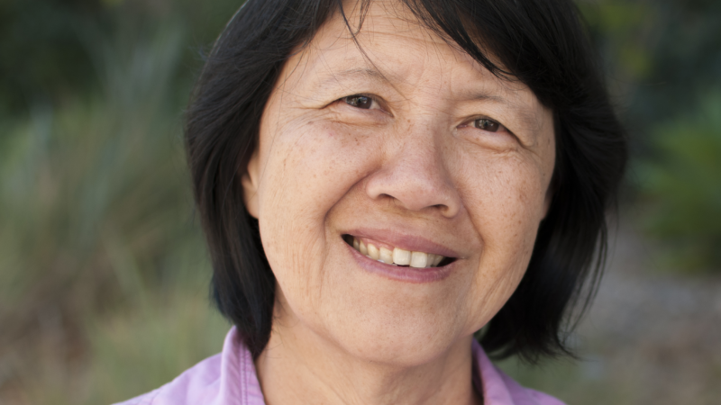 A smiling woman with black hair stands outdoors, embodying community engagement and inclusivity in Los Angeles County.