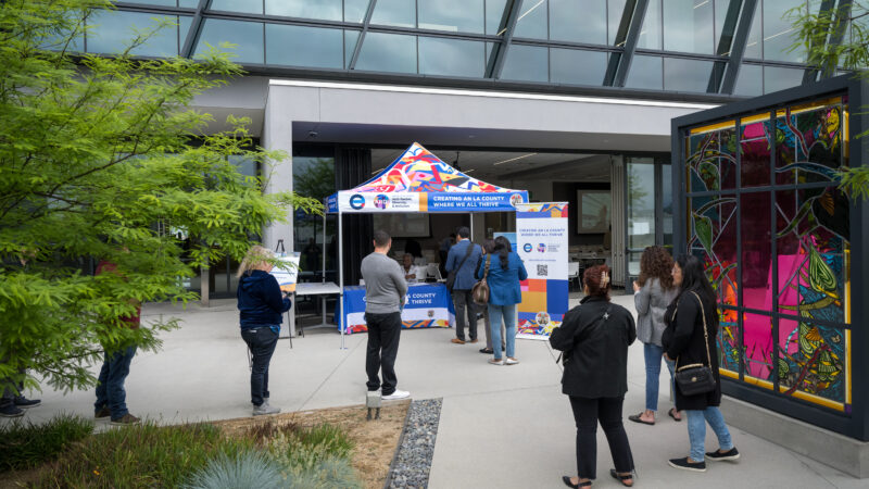 People standing outside waiting to enter a building.