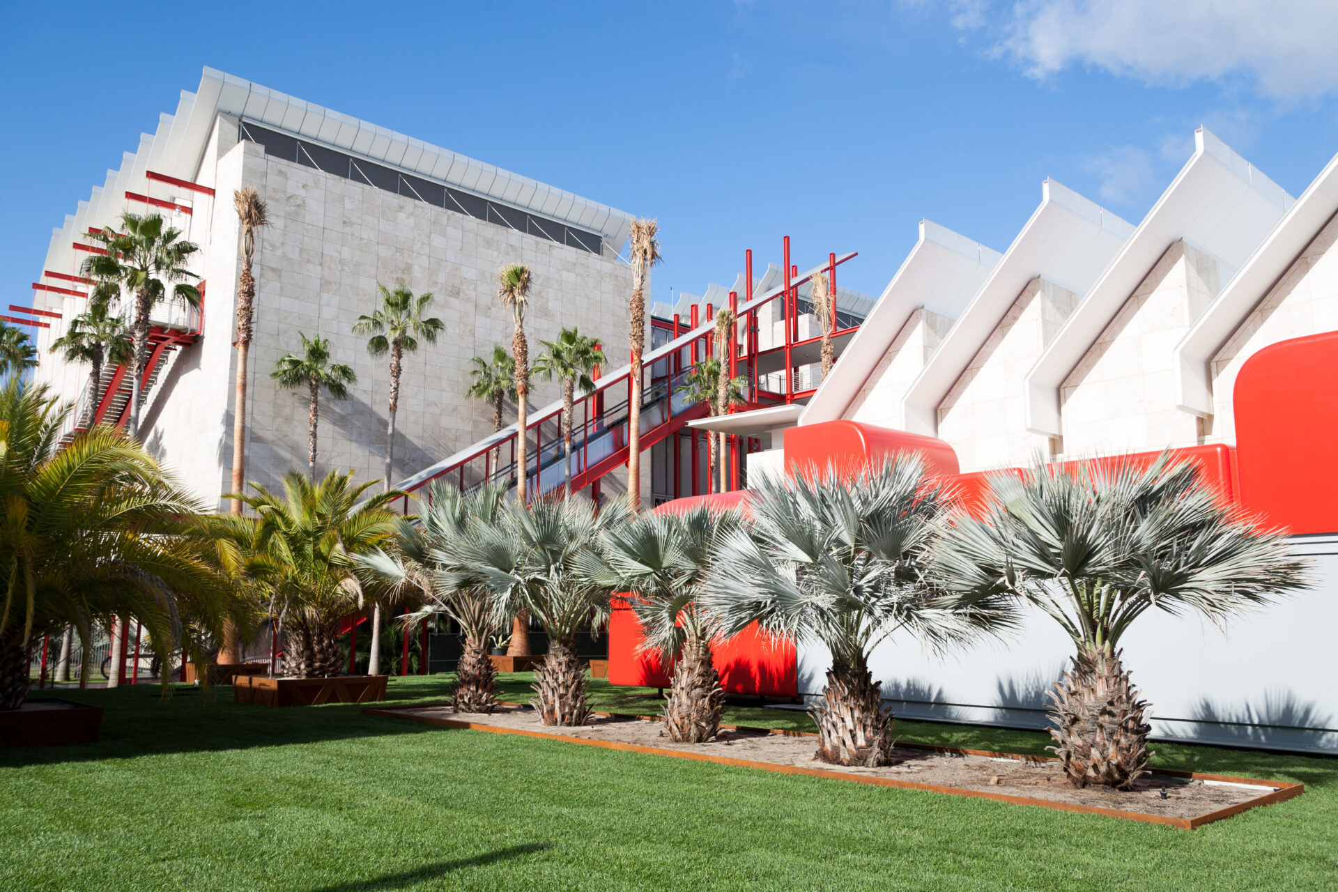 Modern architectural design featuring palm trees and vibrant red accents, highlighting community spaces in Los Angeles County.