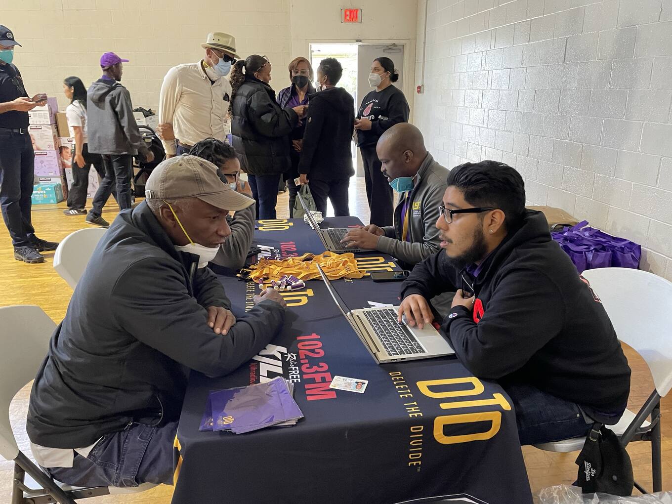 Community members engage in a resource fair, discussing initiatives at a table with informational materials and laptops.