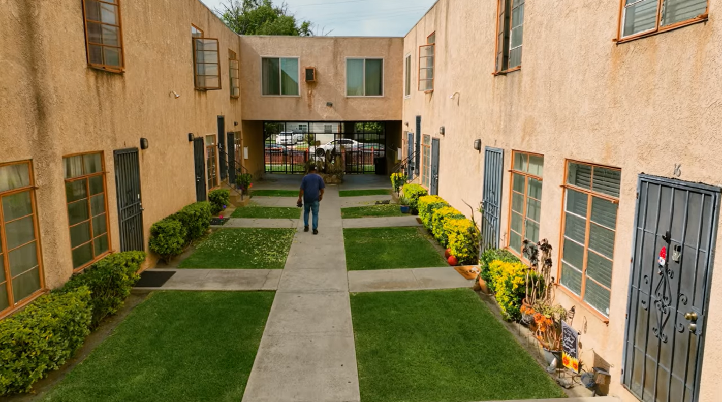 A resident walks through a landscaped courtyard of an apartment complex, highlighting community living and engagement.