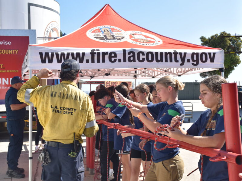 Youth participants engage in hands-on fire safety training under the Los Angeles County Fire Department tent.