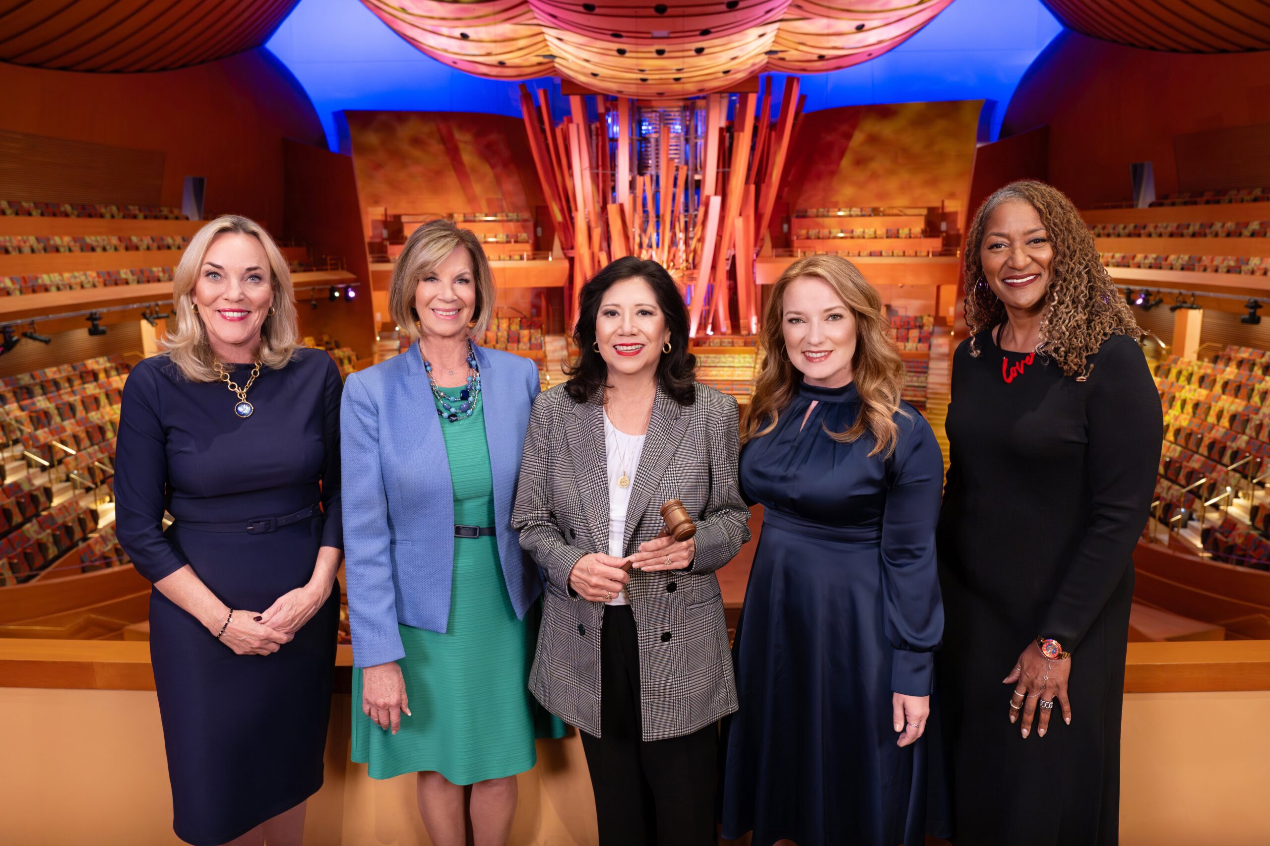 Five women leaders stand together in a vibrant auditorium, symbolizing community empowerment and collaboration in Los Angeles County.