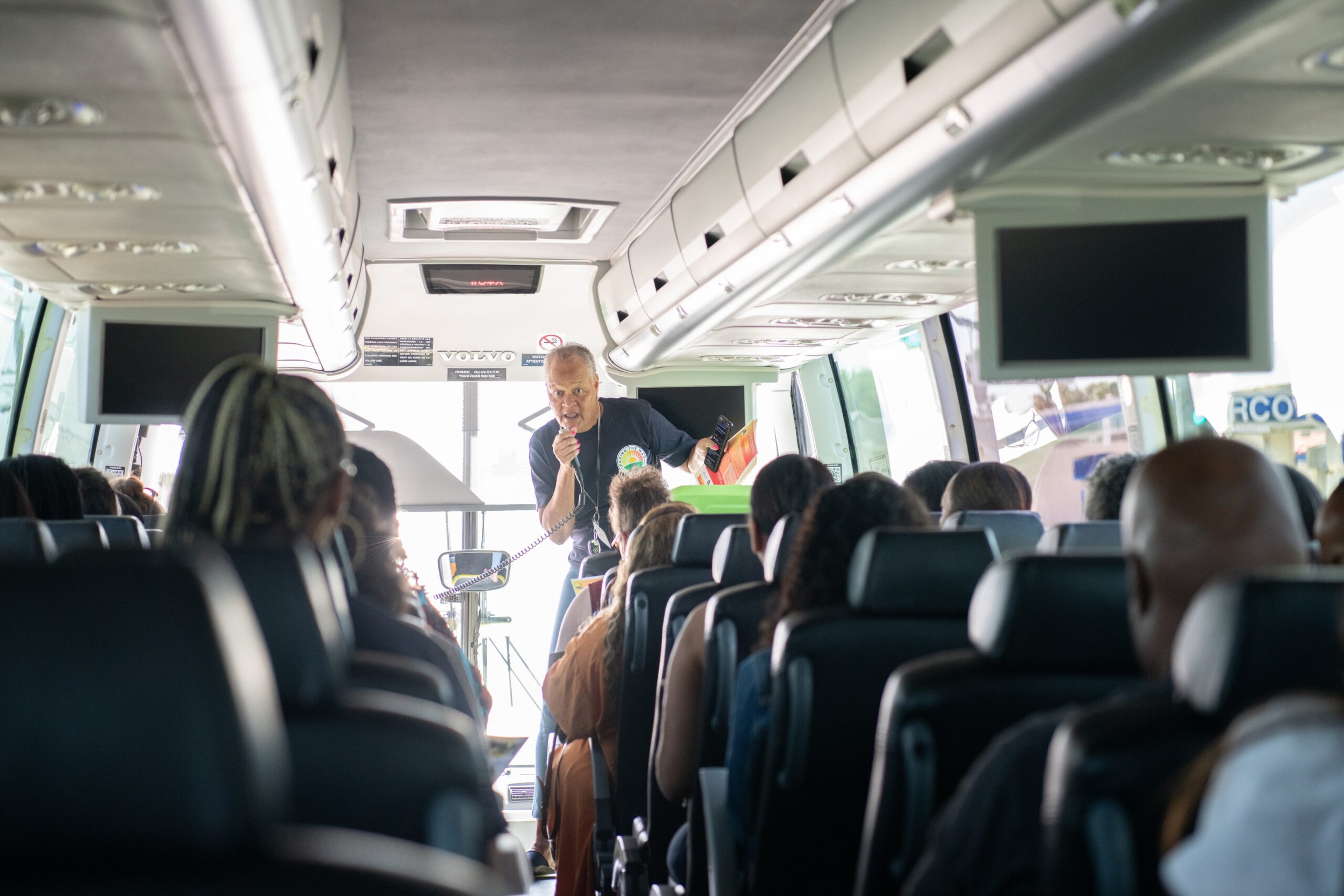 A community leader engages with participants on a bus, fostering dialogue about social equity and community initiatives.