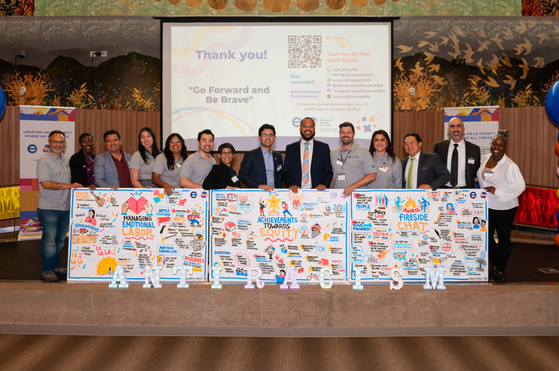 Group stands in front of three boards with text and drawings on them.