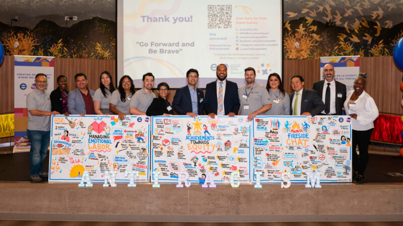 Group stands in front of three boards with text and drawings on them.
