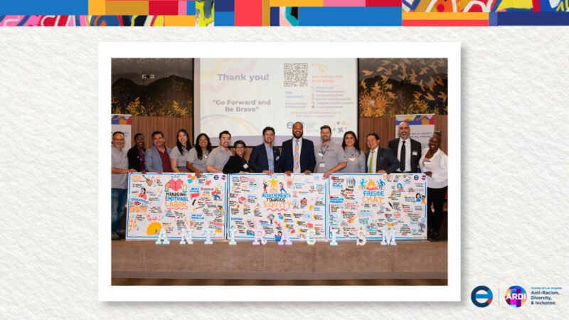 Group stands in front of three boards with text and drawings on them.