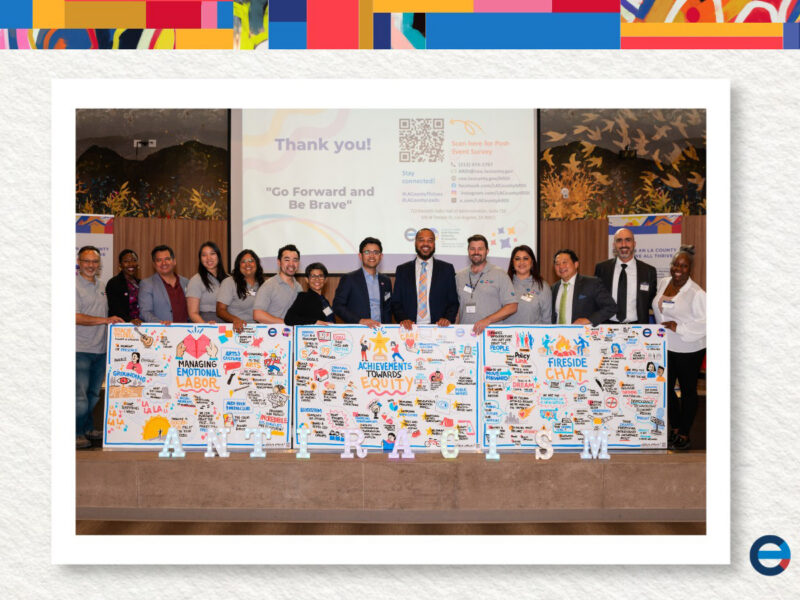 Group stands in front of three boards with text and drawings on them.